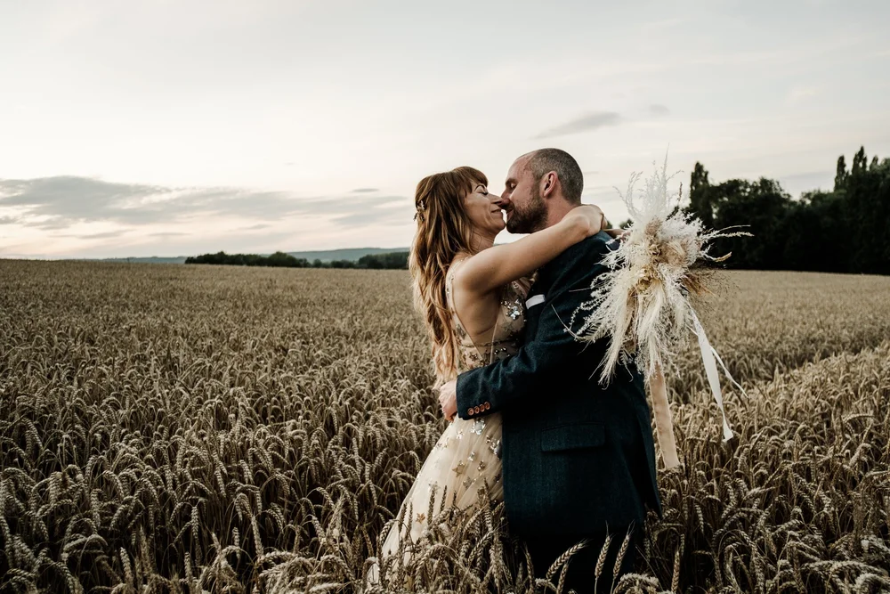 Jess and Tom kissing in the wheat field at Lyde Court at sunset