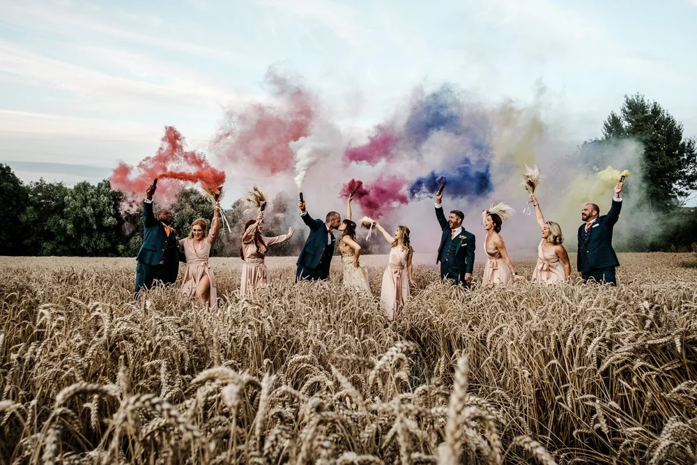 Guests setting off coloured smoke grenades in the wheat field at Lyde Court