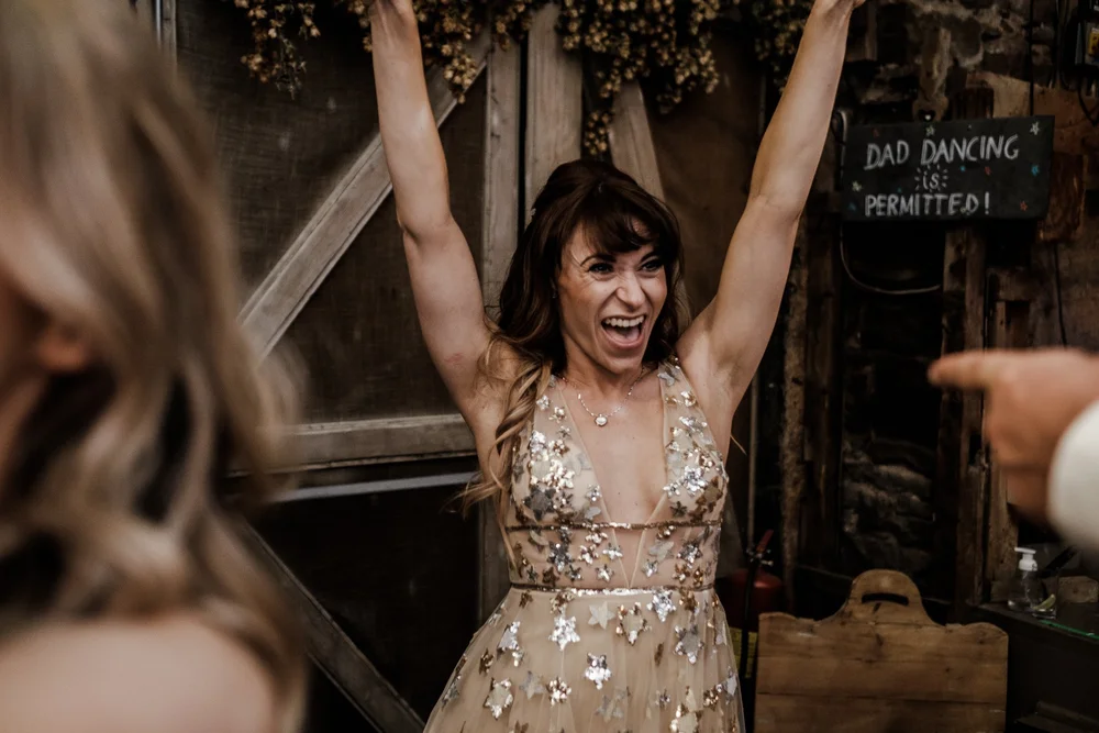 A guest celebrating with her arms in the air on the dance floor