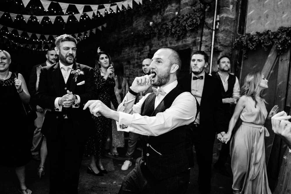 Black and white photograph of guests singing together on the dance floor