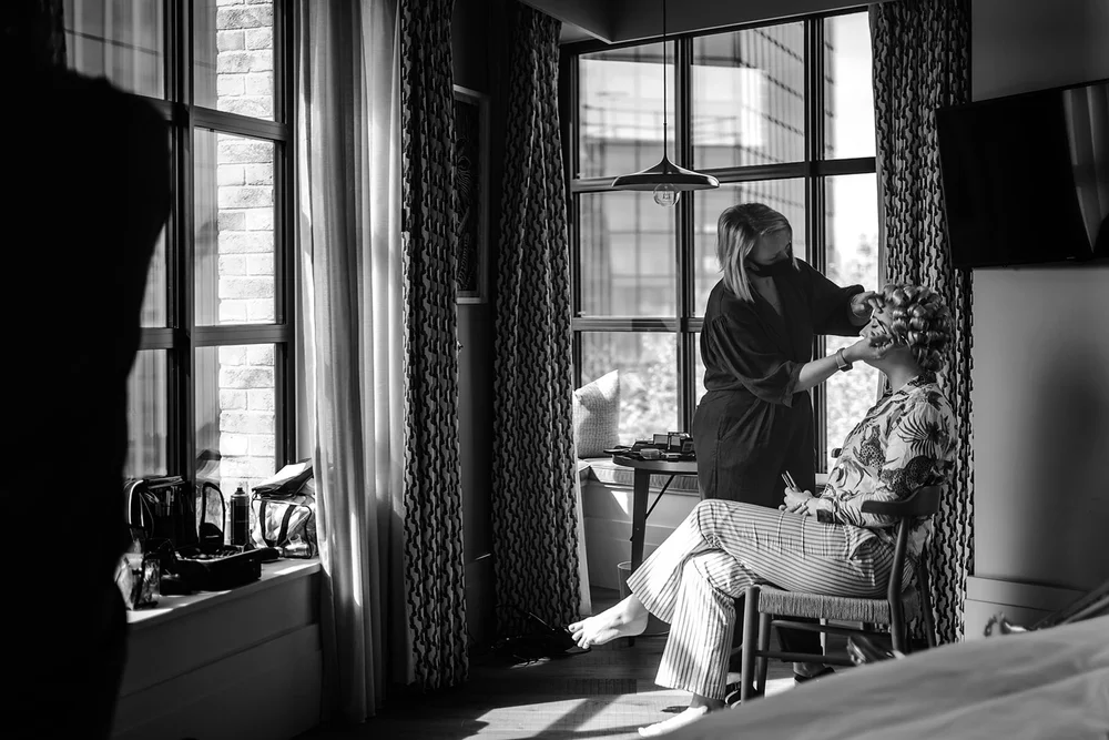 Black and white photograph of Meg getting ready in the window light at The Hoxton