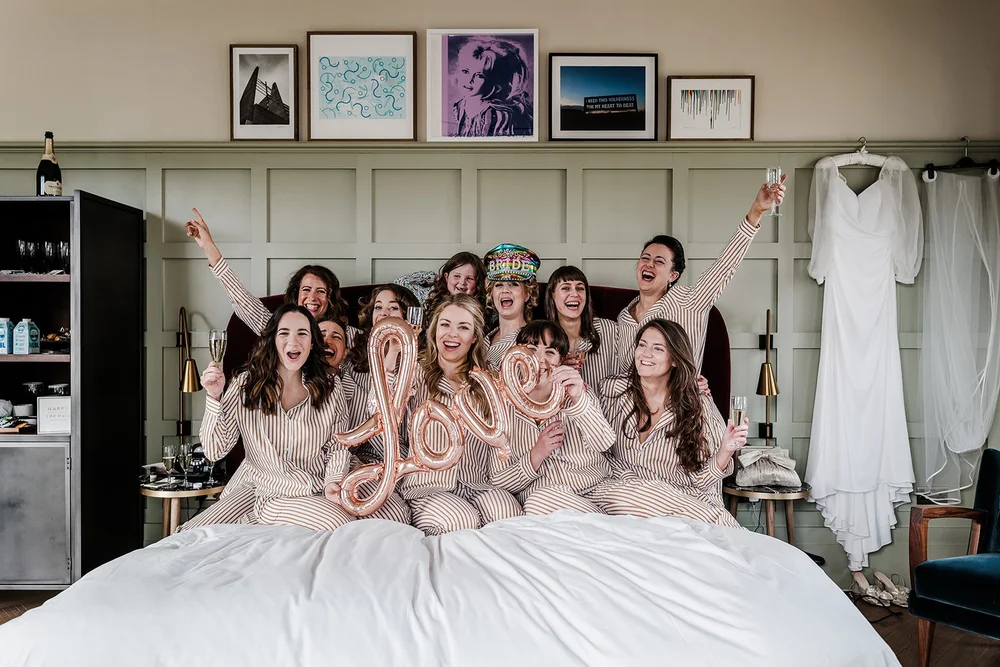 Meg and her bridesmaids on the bed in their robes before the wedding