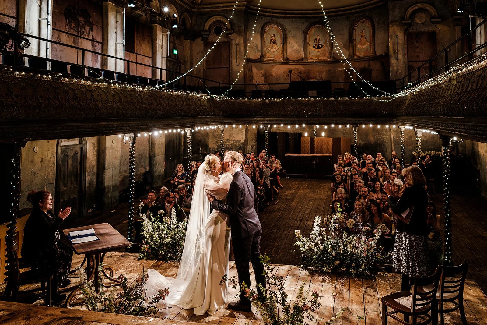 Meg and Jamie kissing on the stage at Wilton&rsquo;s Music Hall after their vows
