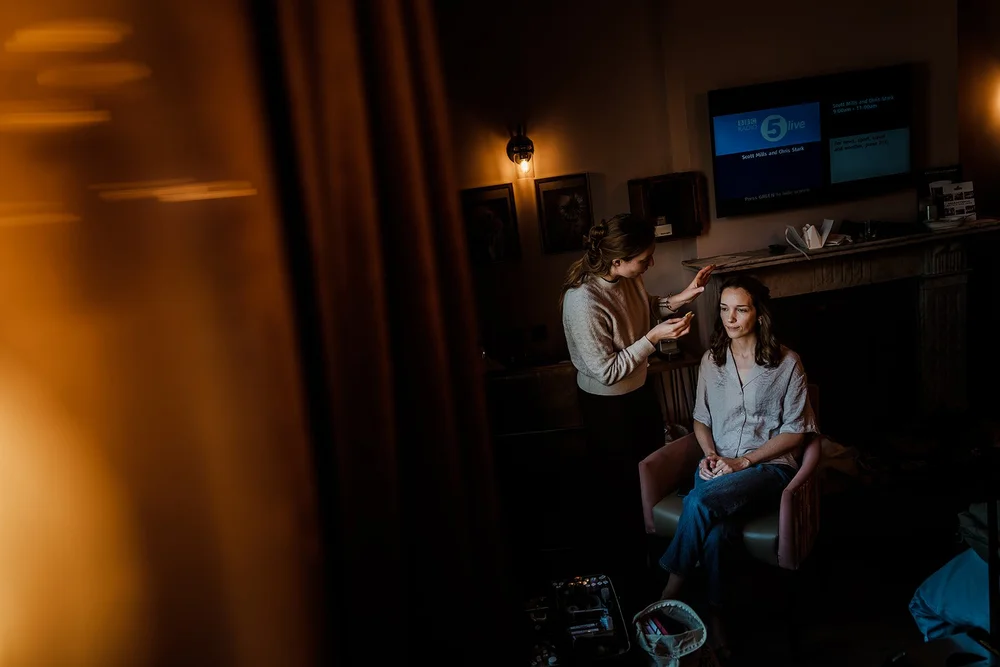 Charlotte getting ready in warm lamplight on the morning of the wedding