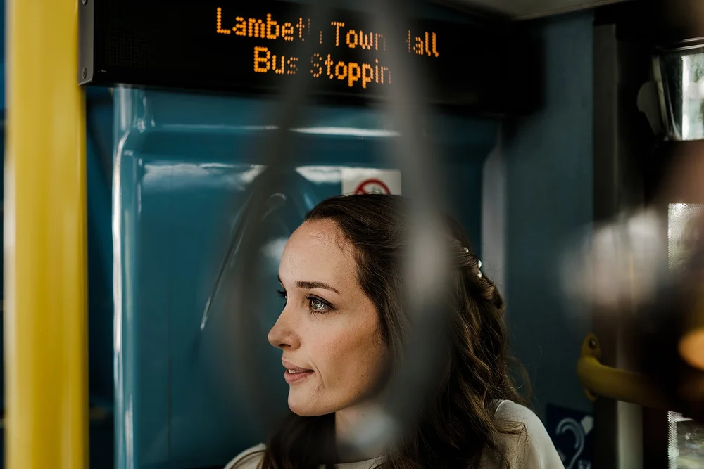 Charlotte reflected in the window of a bus stop outside Lambeth Town Hall