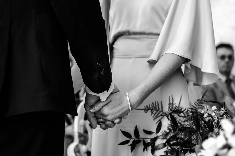 Black and white detail of Aidan and Charlotte holding hands during the ceremony