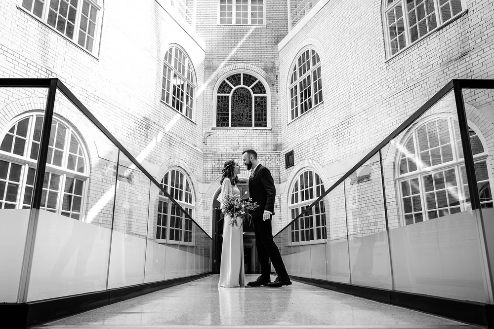 Black and white photograph of Aidan and Charlotte in the arched walkway at Lambeth Town Hall