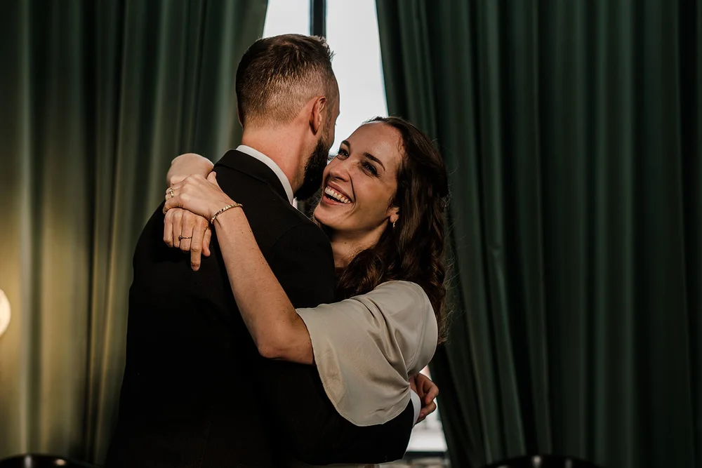 Aidan and Charlotte holding each other against a green velvet curtain