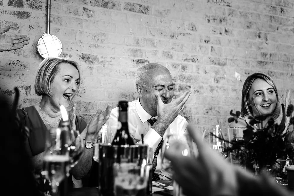Black and white photograph of guests reacting to a wedding speech