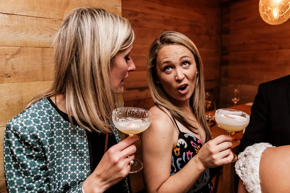 Two guests laughing with cocktails during the evening