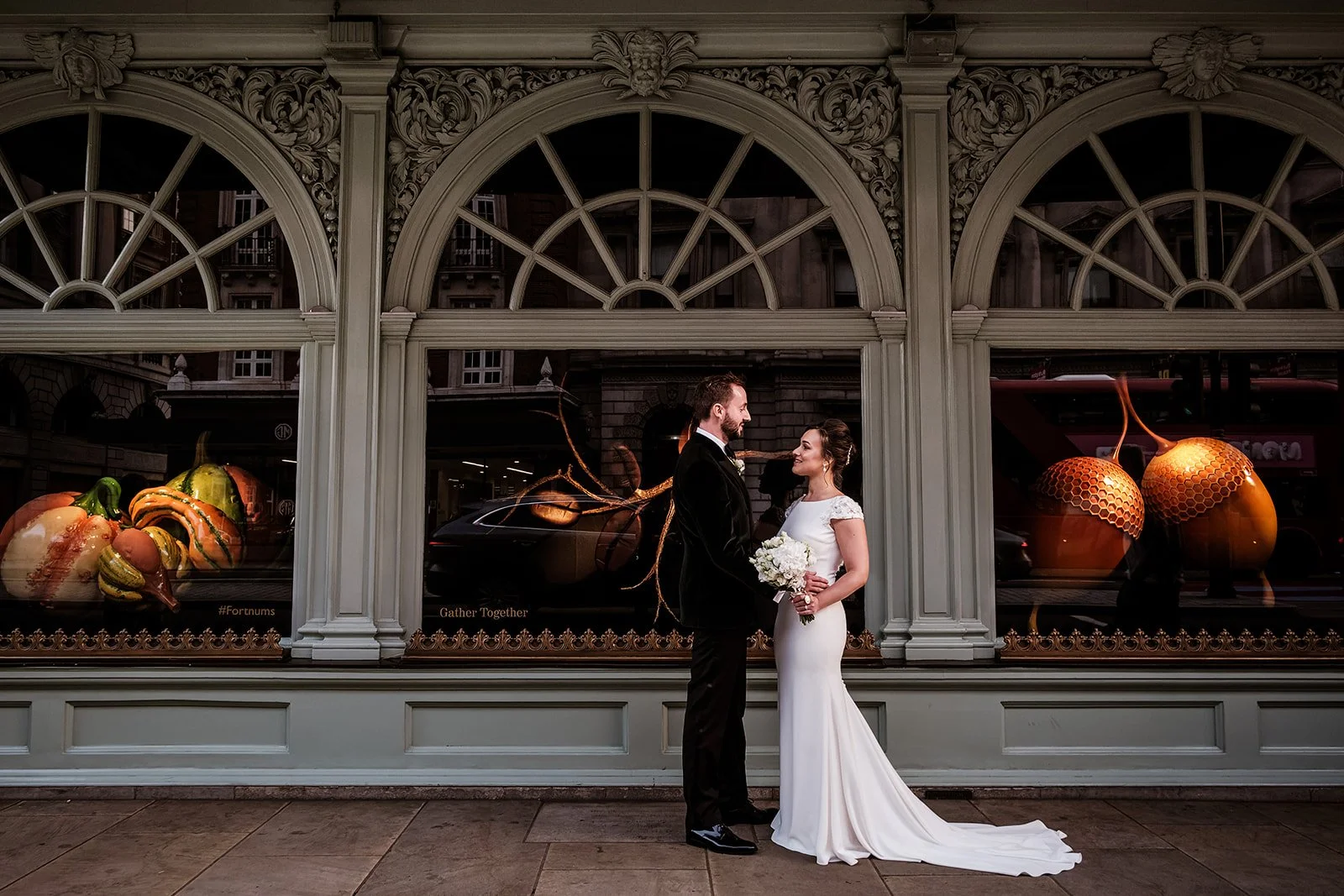 The couple beneath the arcaded windows of Fortnum & Mason in the evening