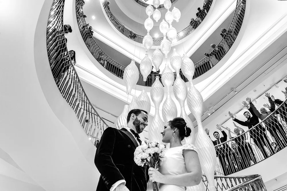 Petals falling over the couple on the spiral staircase at Fortnum & Mason