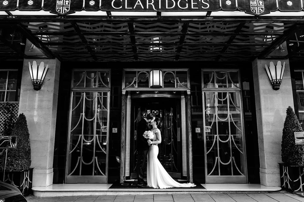Black and white photograph of the couple beneath the Claridge&rsquo;s canopy on Brook Street