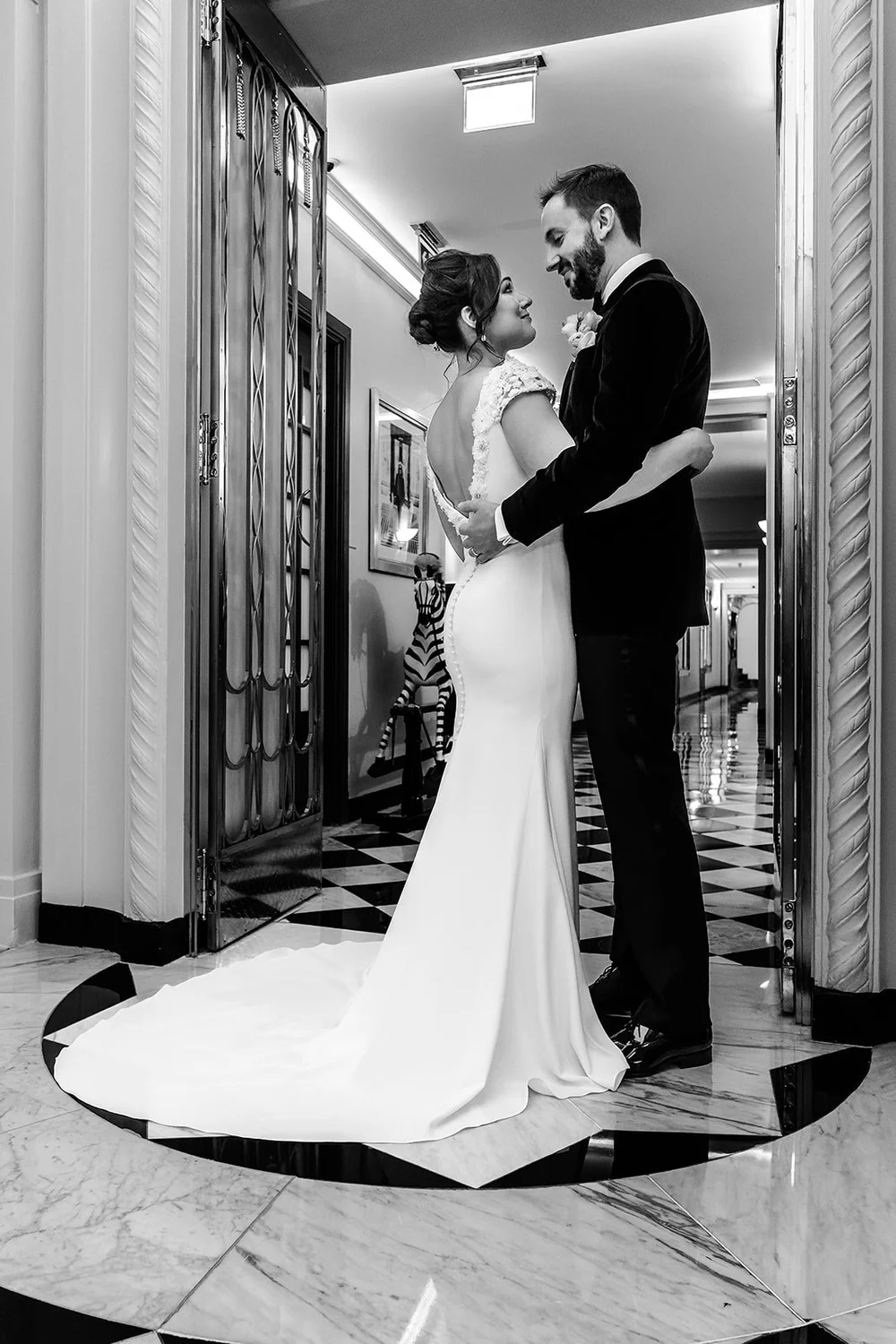 Black and white photograph of the couple embracing in the lobby at Claridge&rsquo;s