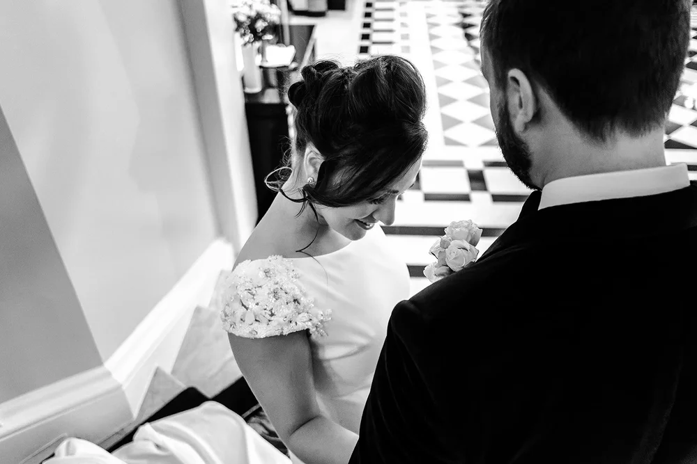 Black and white photograph of the bride having her veil adjusted at Claridge&rsquo;s