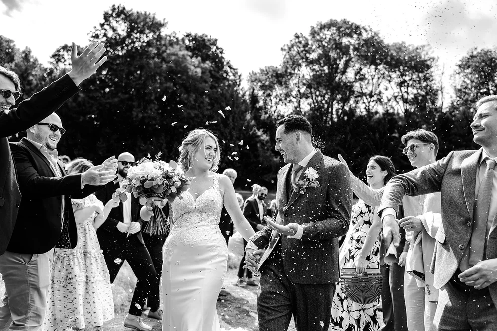 Black and white photograph of confetti thrown over Liv and Jack at Hadsham Farm