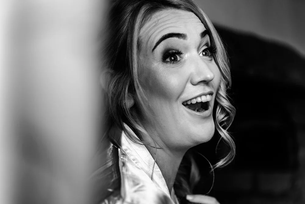 Black and white photograph of Liv laughing during preparations before her Hadsham Farm wedding