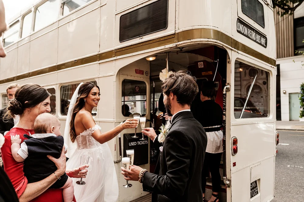 Wedding guests toasting on board a vintage Routemaster bus after a Chelsea wedding