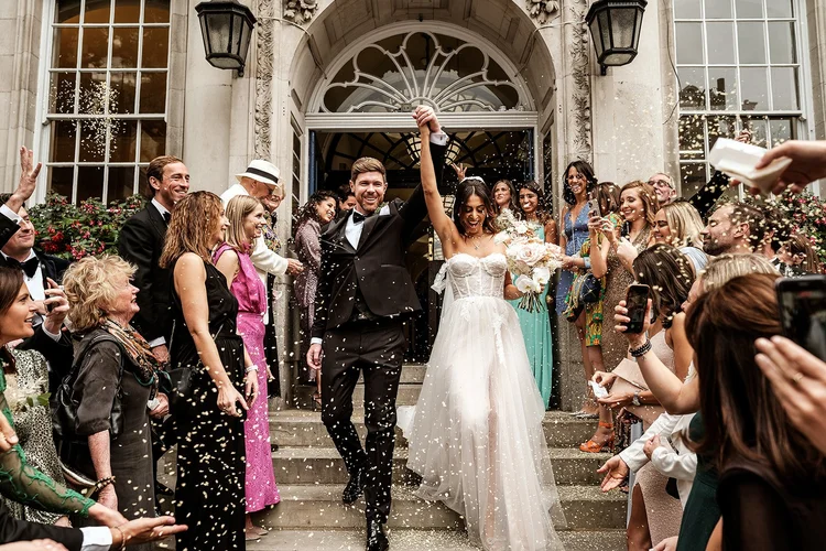Sara and Chris on the steps of Chelsea Old Town Hall surrounded by confetti