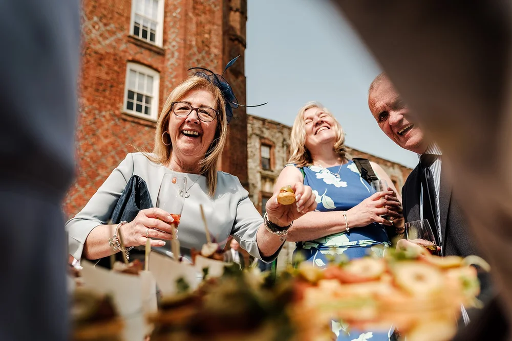 Guests laughing together during the wedding breakfast at Farnham Castle