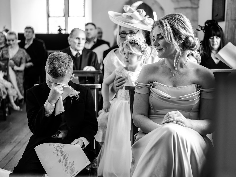 Black and white photograph of a guest wiping away a tear during the ceremony