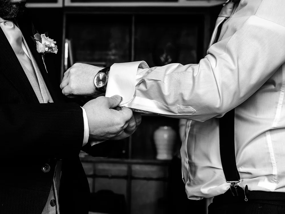 Black and white detail of cufflinks being fastened before the wedding