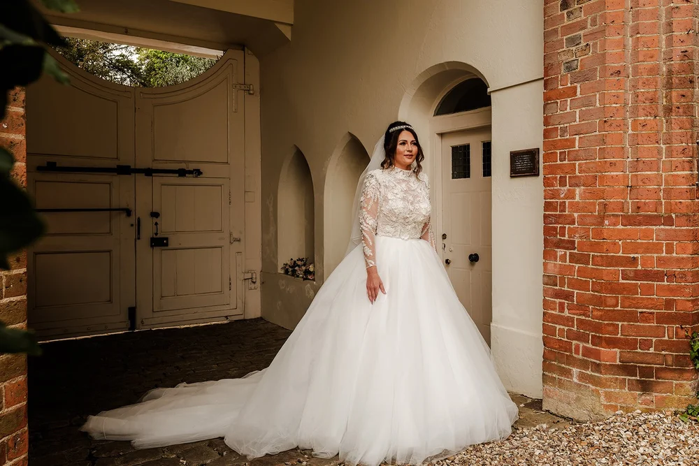 Jade in her wedding dress in the brick archway at Farnham Castle