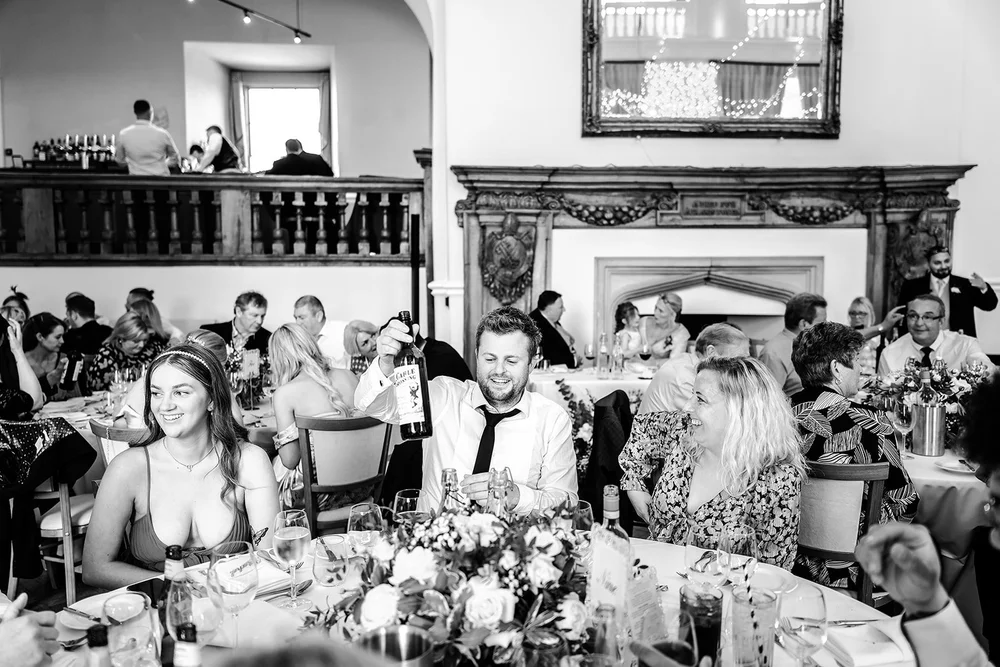Black and white photograph of guests laughing during dinner at Farnham Castle