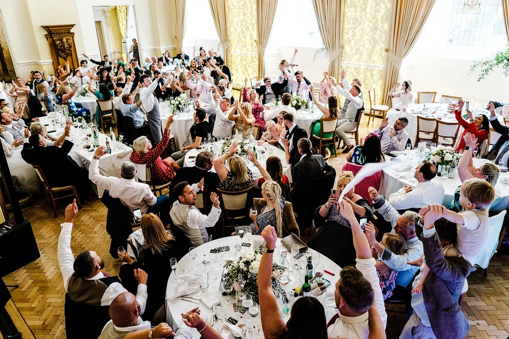 Guests with their hands in the air as the singing waiters perform at Farnham Castle