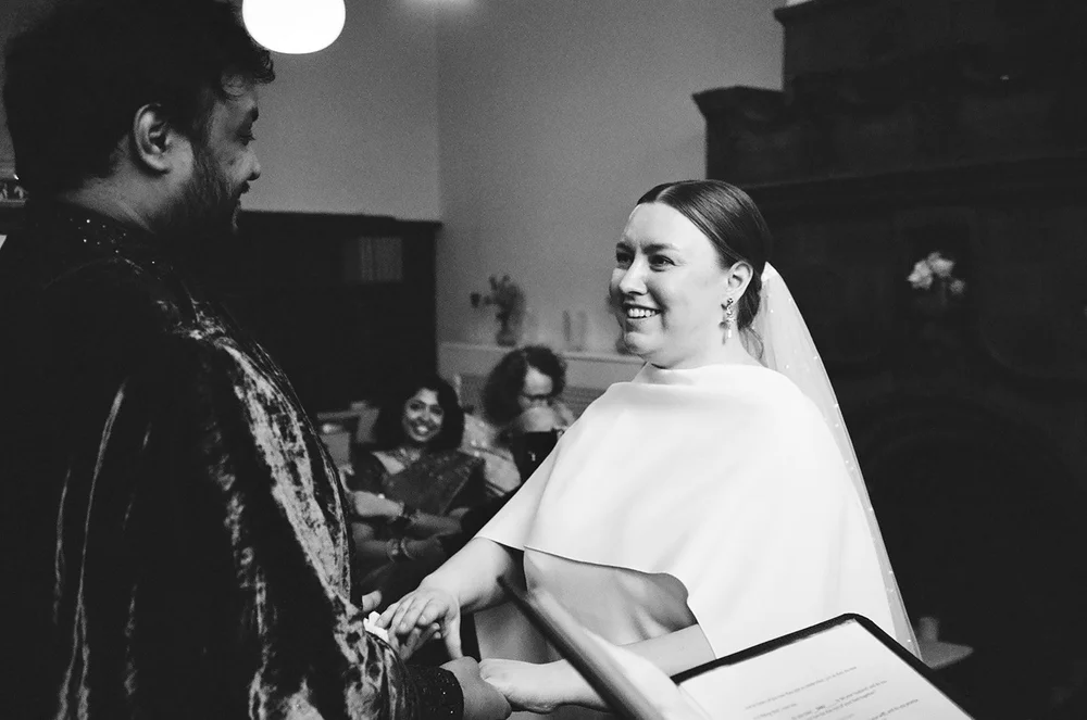 Bride laughing with a guest during the reception, shot on 35mm black and white film