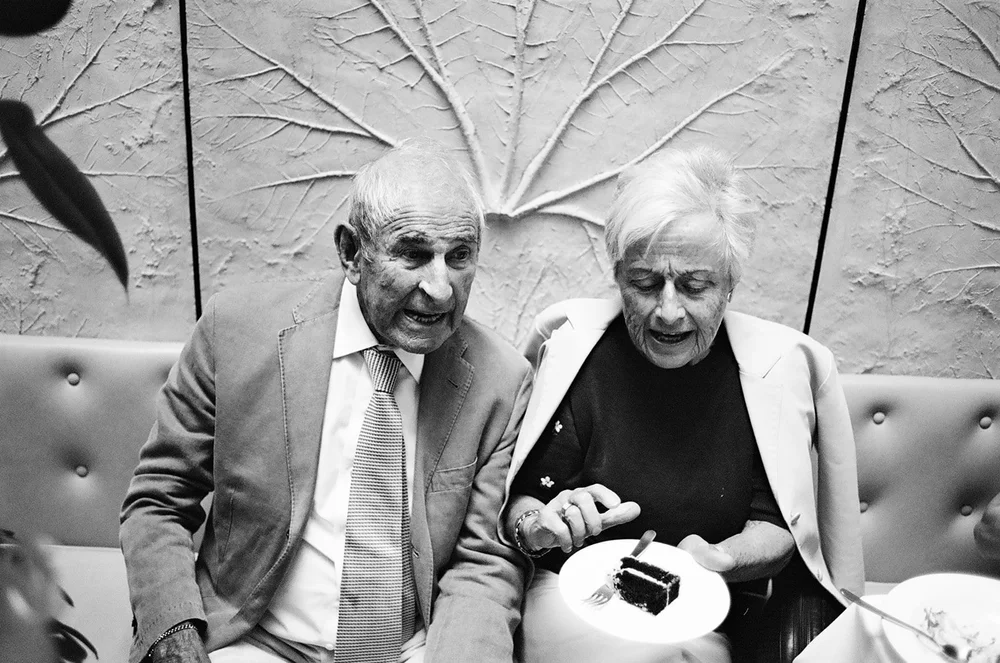 Two older wedding guests sitting together, photographed on 35mm black and white film