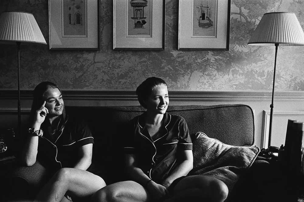 Black and white 35mm film photograph of guests relaxing on a sofa