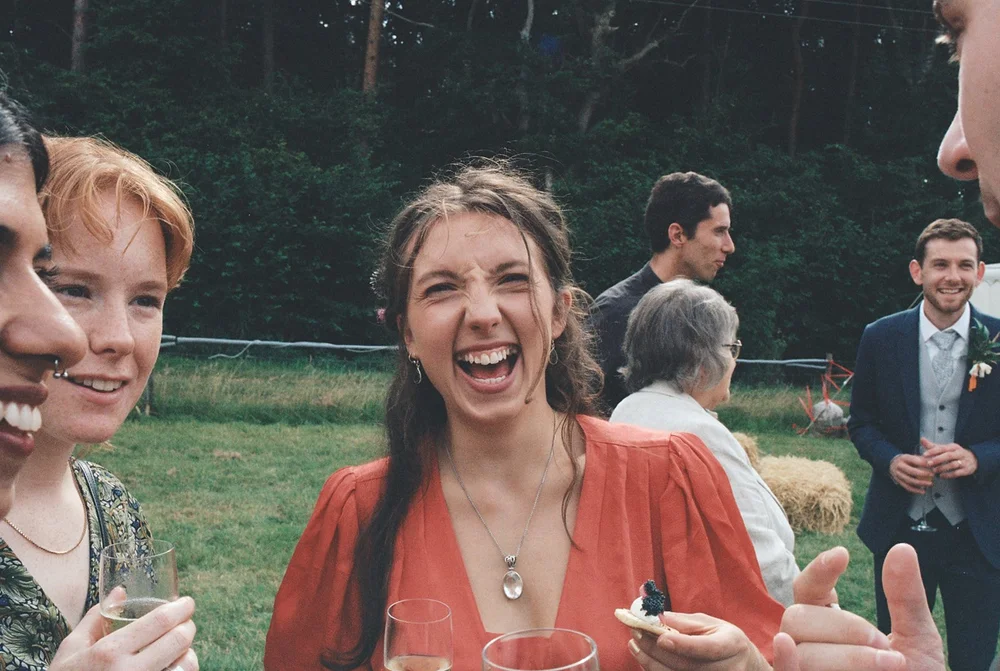 Wedding guests laughing together outdoors, photographed on Kodak Portra 400