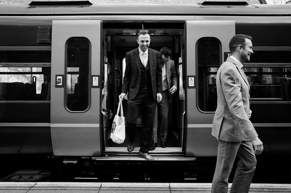 Tom stepping off the train in his suit on the way to All Saints, Clifton