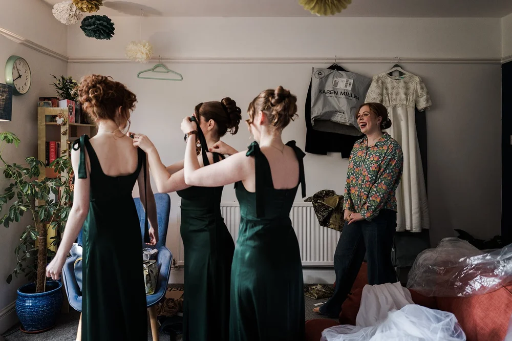 Bridesmaids helping each other into their dresses before the wedding
