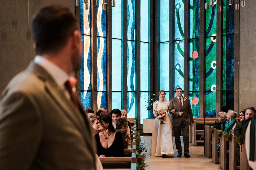 Ffion walking down the aisle at All Saints, Clifton, the stained glass behind