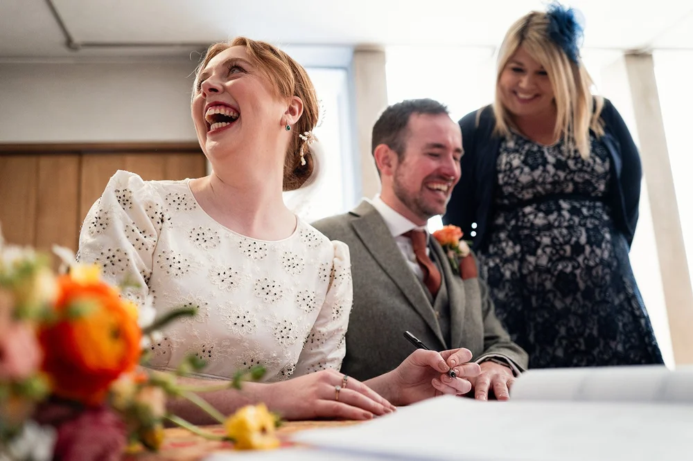 Ffion laughing while signing the register at All Saints, Clifton