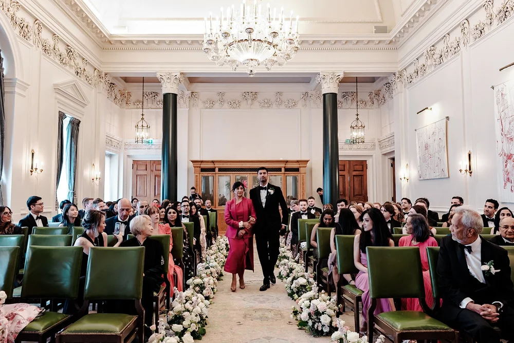 A wedding ceremony in the Saloon at The Ned, guests seated in green chairs