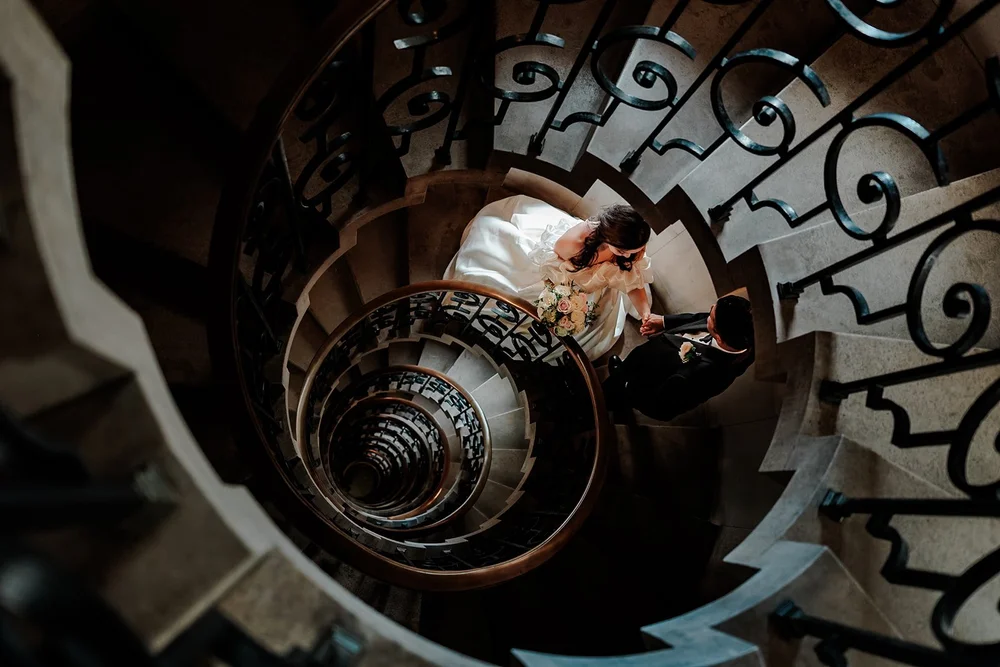 Looking down the spiral staircase at The Ned as a couple stand at the bottom