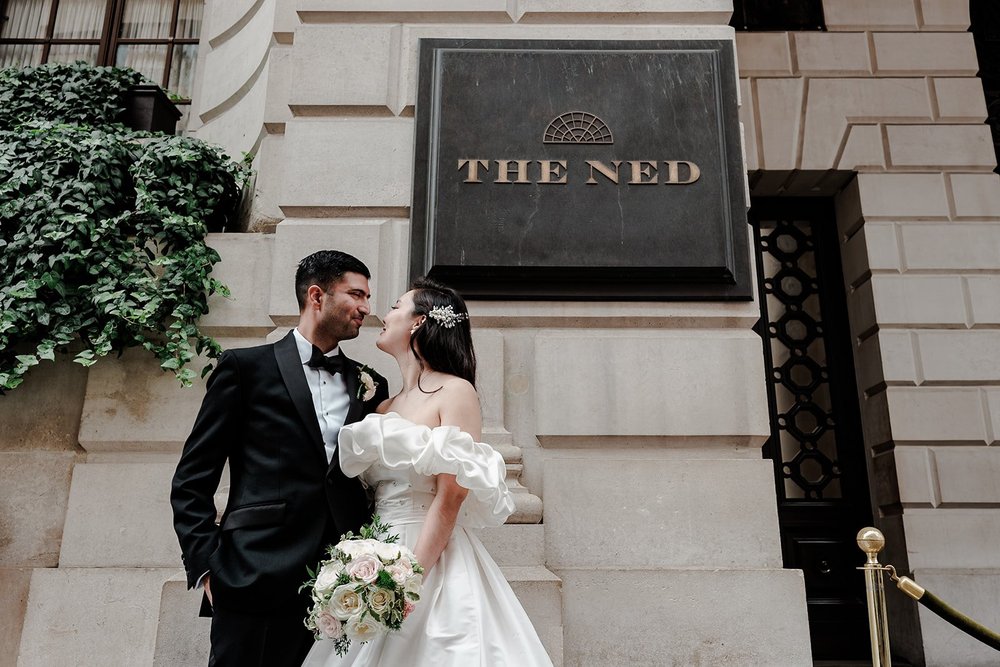 A couple kissing beneath The Ned sign on Poultry in the City of London