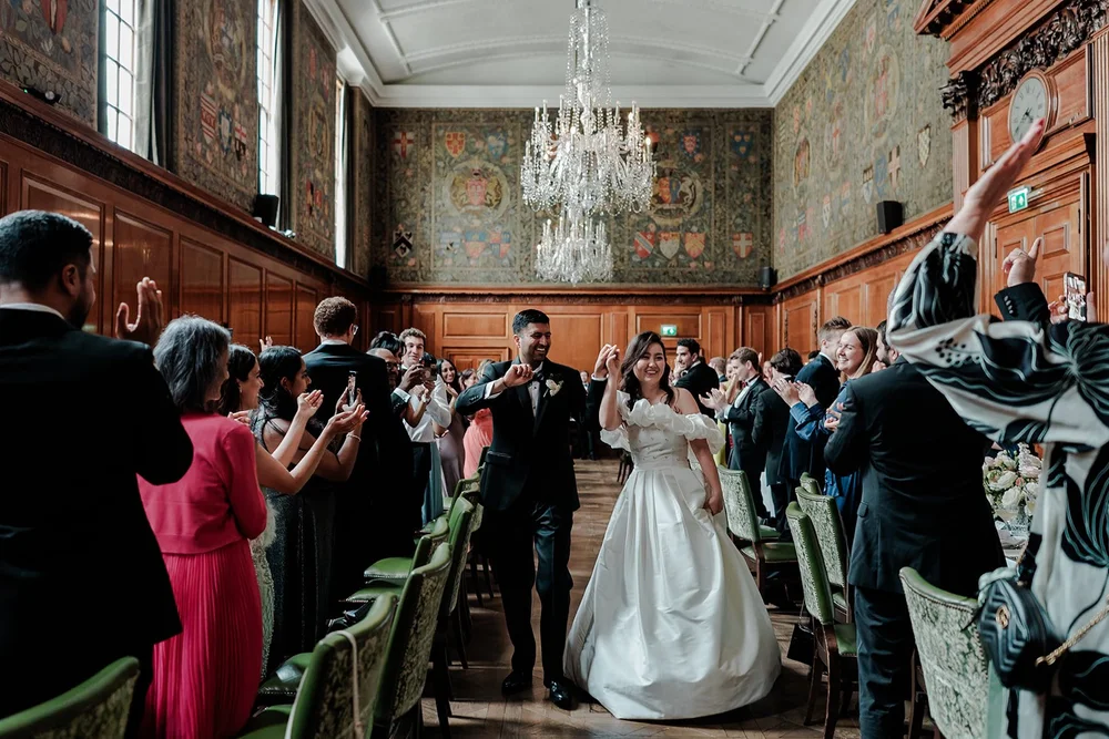 A couple leaving the Tapestry Room to applause after their ceremony at The Ned