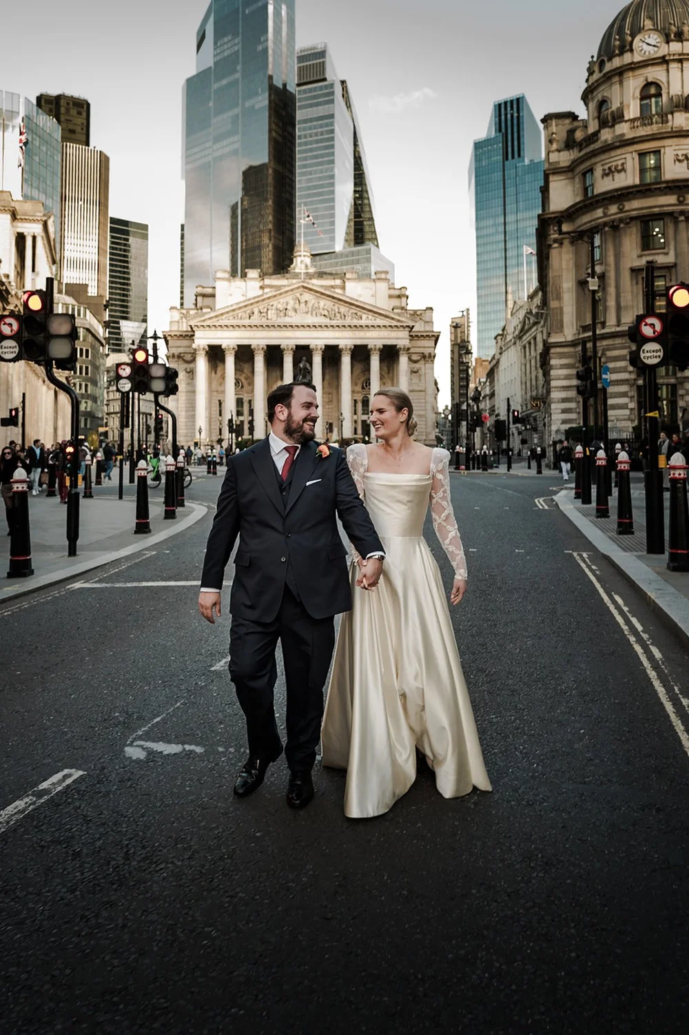 Bride and groom walking through the City of London outside The Ned, the Royal Exchange behind
