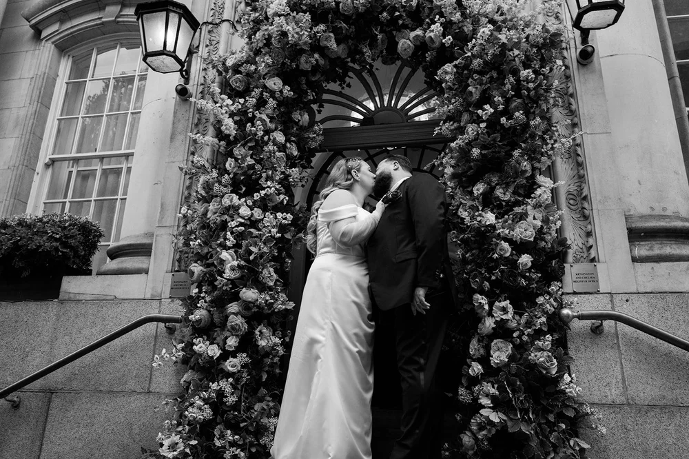 A kiss under the flower archway at Chelsea Old Town Hall