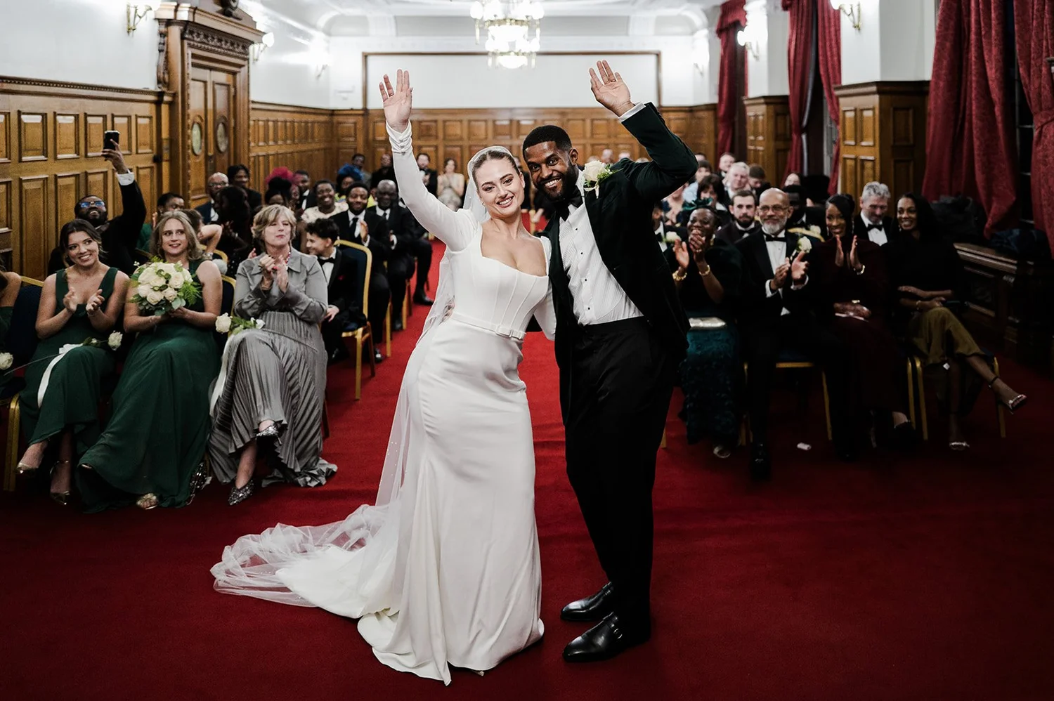 Sophie and Dan walking back down the red carpet with their arms in the air after the ceremony