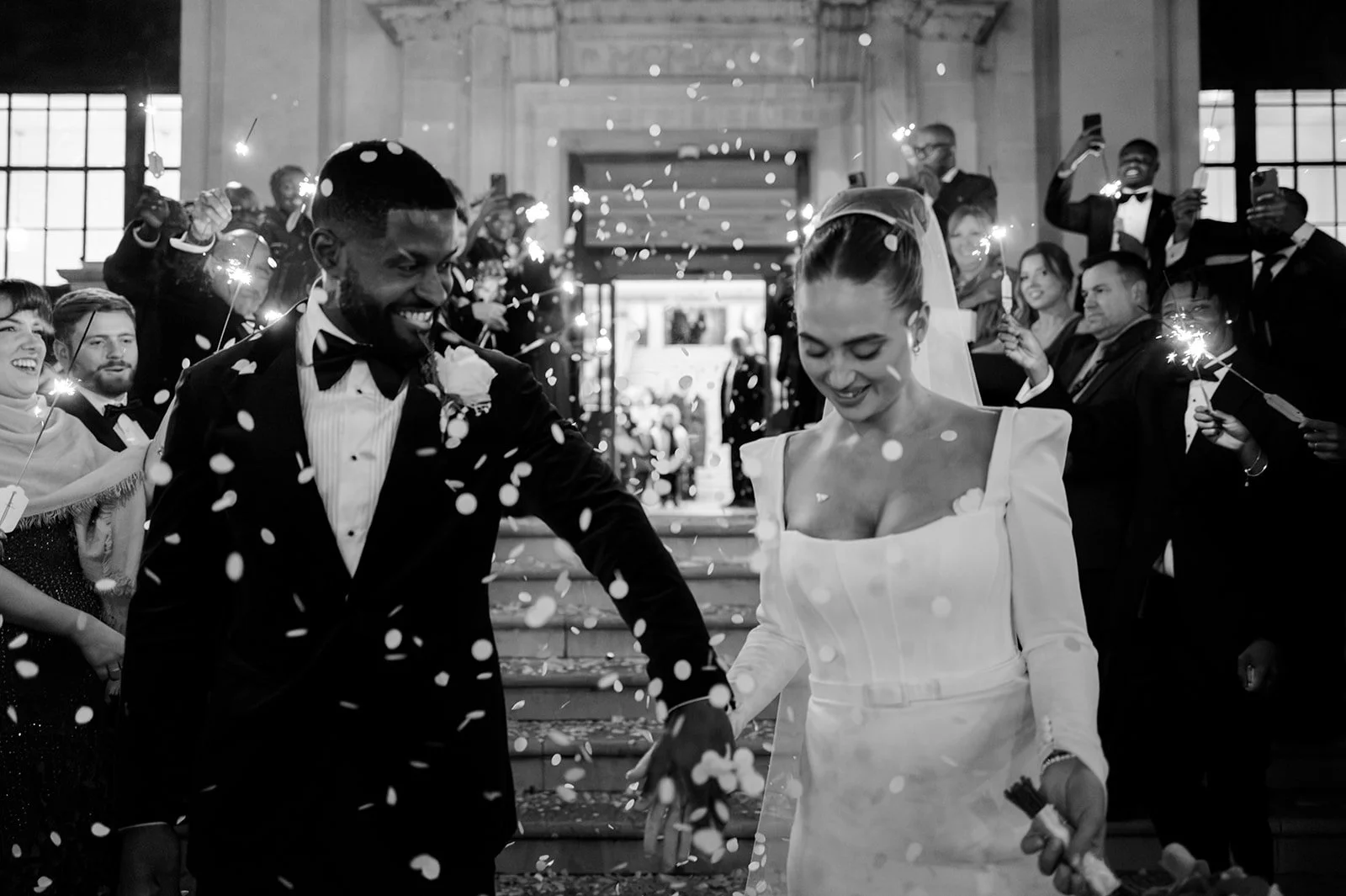 Sophie and Dan walking through a confetti shower on the steps of Islington Town Hall