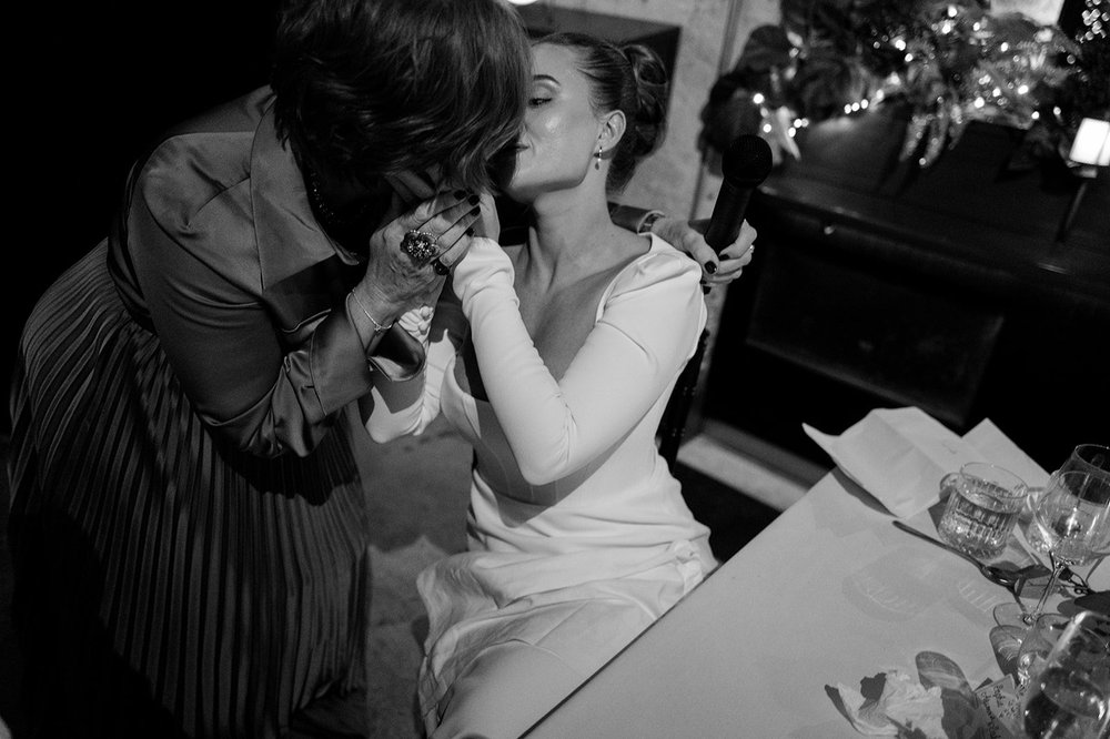 Black and white photograph of Sophie and Dan kissing at the table