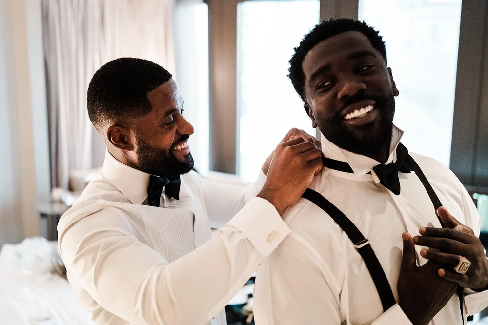 Groomsmen helping Dan with his bow tie before his London wedding