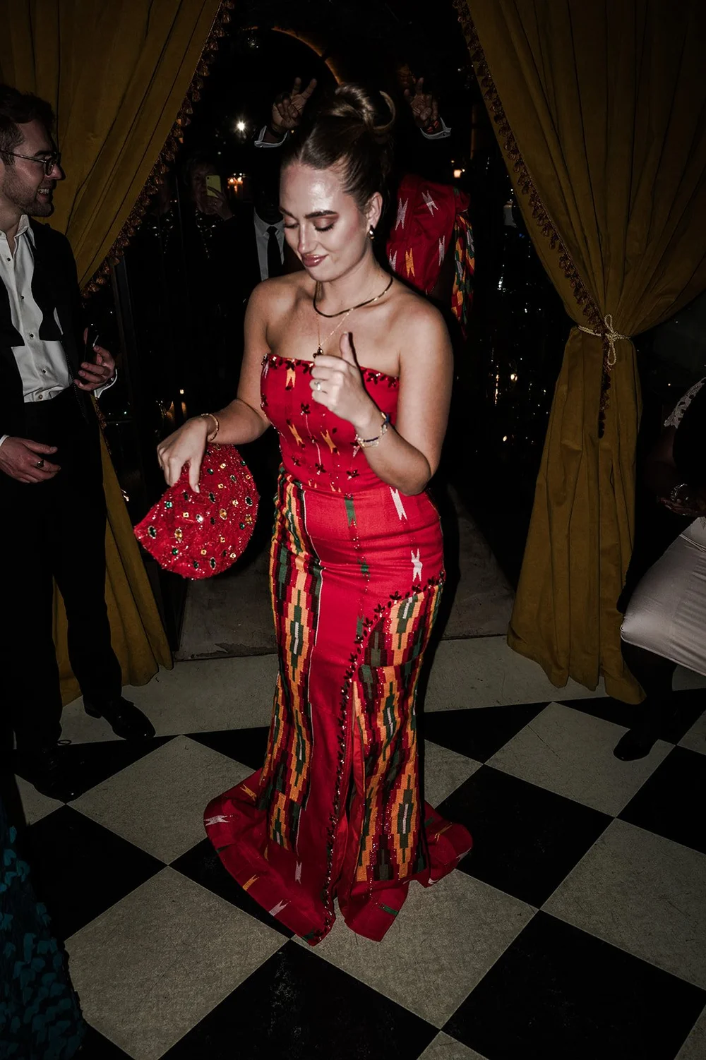 Sophie in a red gown with kente panels after changing into traditional Ghanaian dress