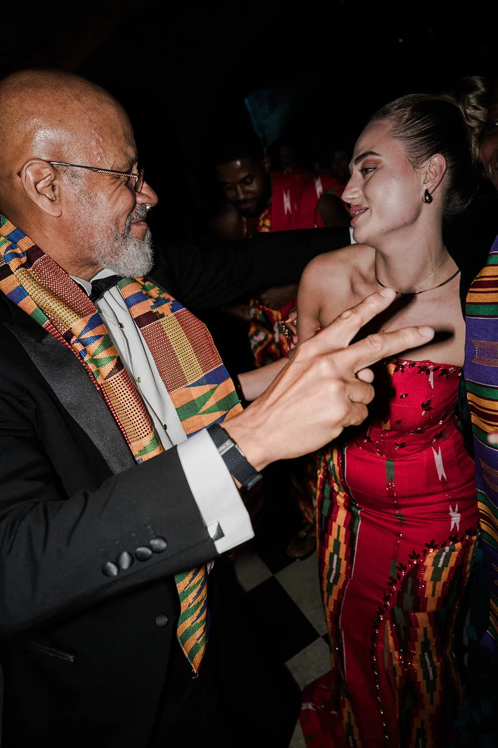 A guest in a kente stole dancing with Sophie at the reception