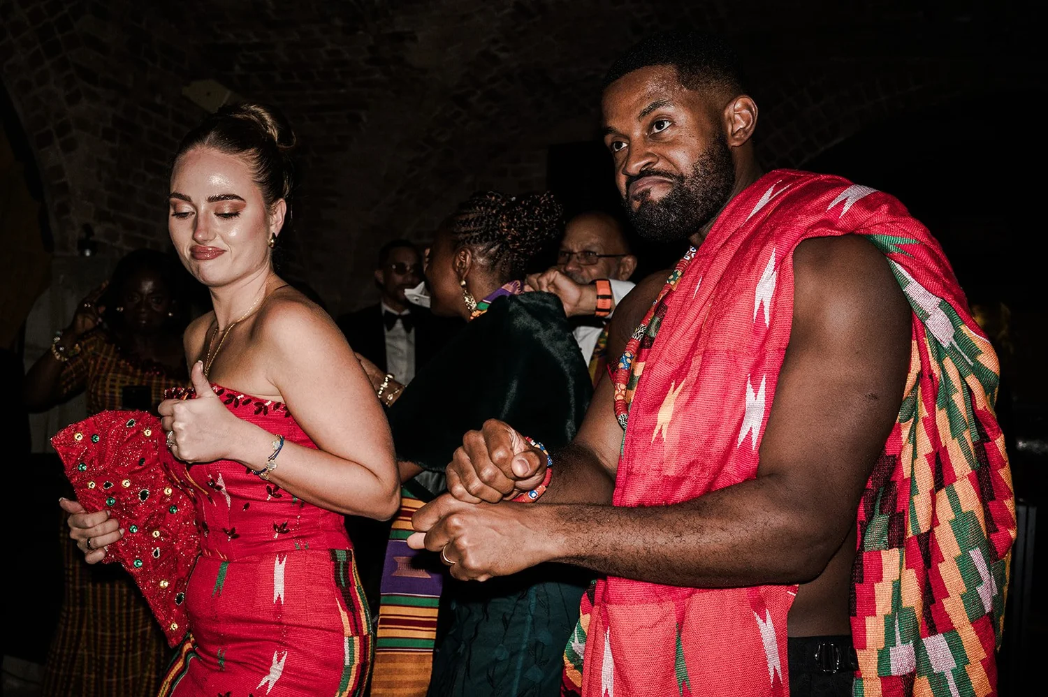 Sophie and Dan hand in hand in traditional Ghanaian dress at the end of the night